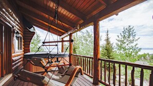 Eine Holzterrasse mit einer Hängemattenliege und Blick auf Bäume und Berge.