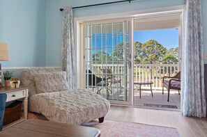 Une chambre avec une grande fenêtre, un lit, une table de chevet et une vue sur le balcon extérieur.