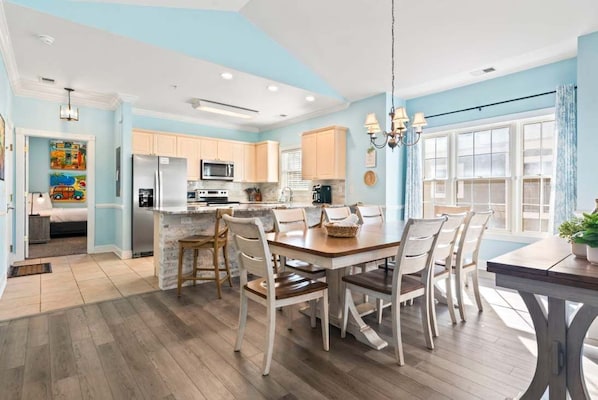 A modern kitchen with a central island, wooden flooring, and light blue walls.