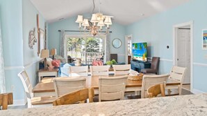 Un espace repas agrémenté d’un lustre, de chaises en bois, d’un comptoir en marbre et offrant une vue sur l’extérieur.