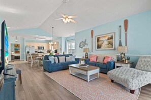 A spacious living room with a blue sofa set, a coffee table, and a patterned rug.