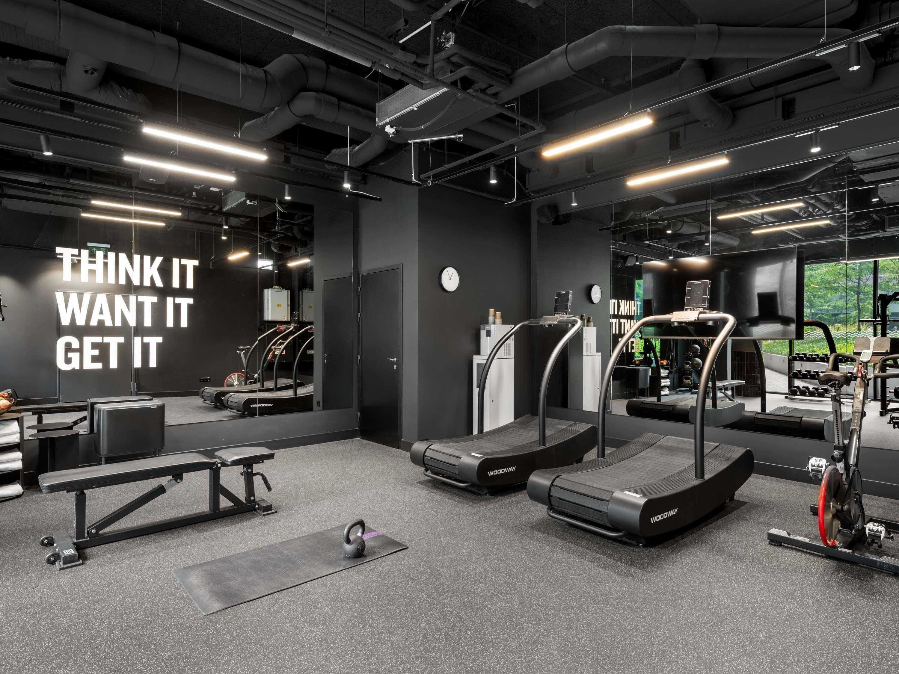 Un gimnasio con cintas de correr, pesas y una frase motivacional en la pared.