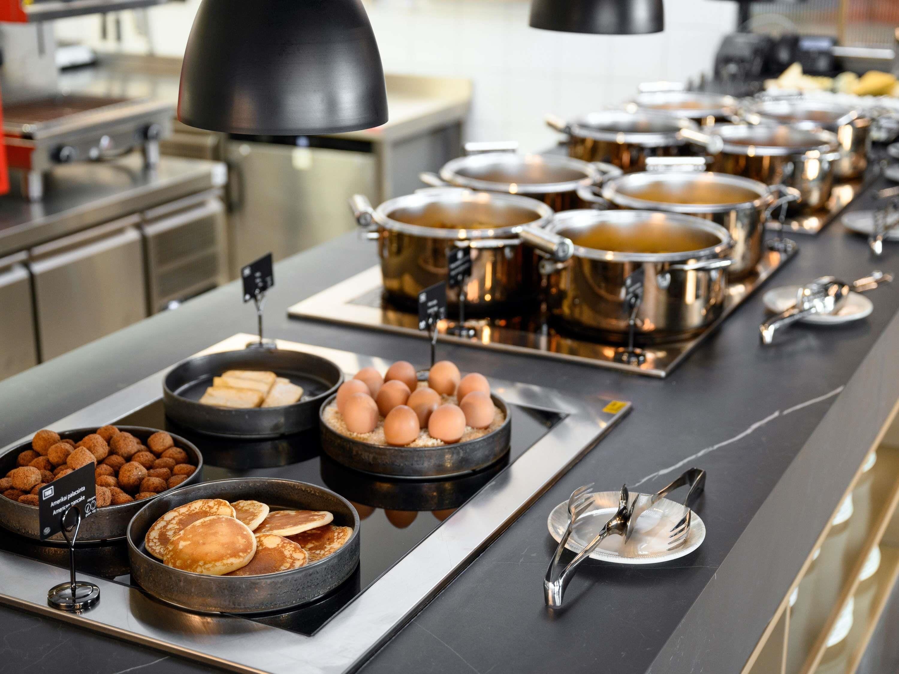 Un buffet proposant une variété de plats, notamment des crêpes, des œufs et des boulettes de viande.