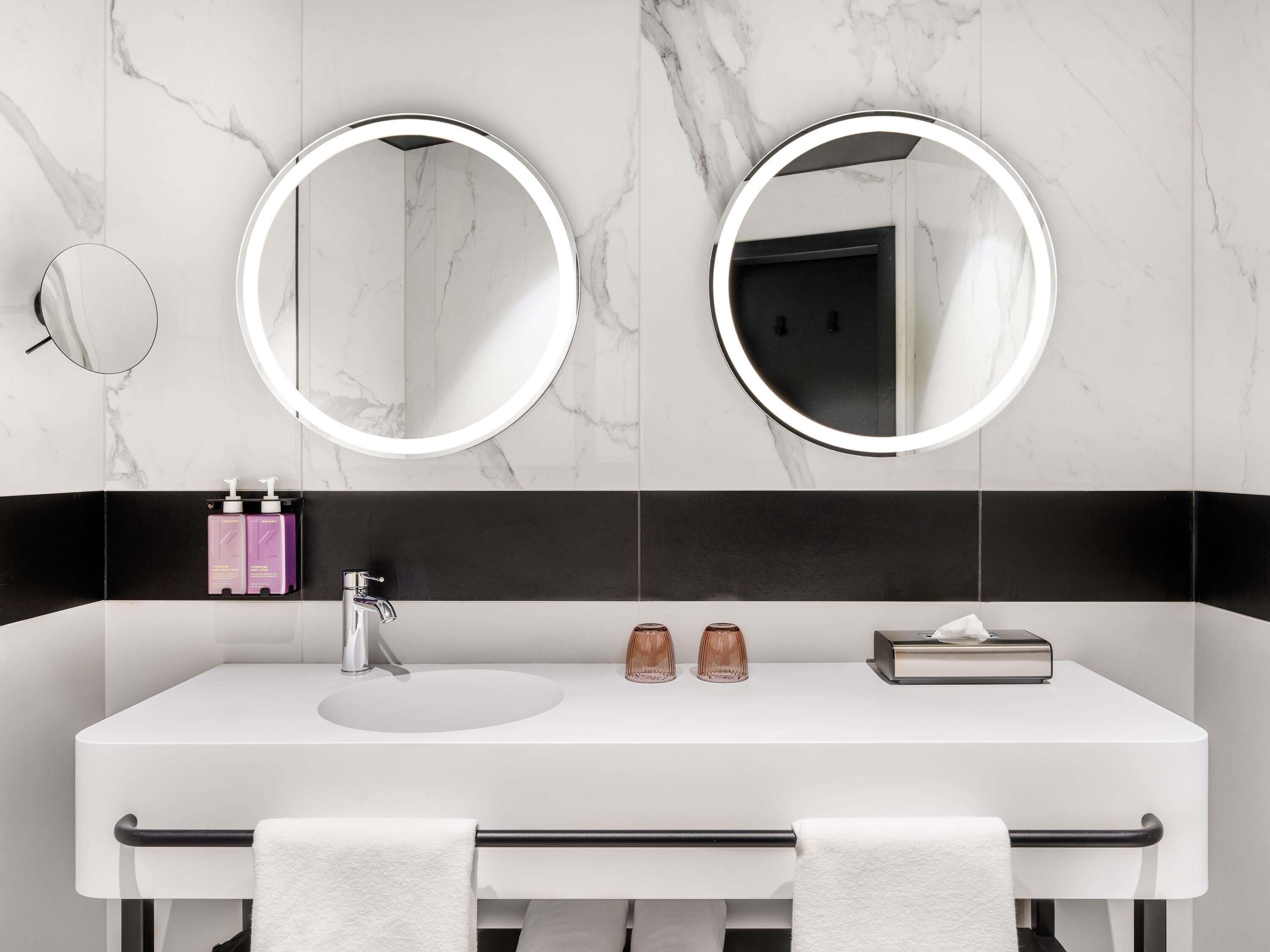 A modern bathroom with two mirrors, a white sink, and a black countertop.