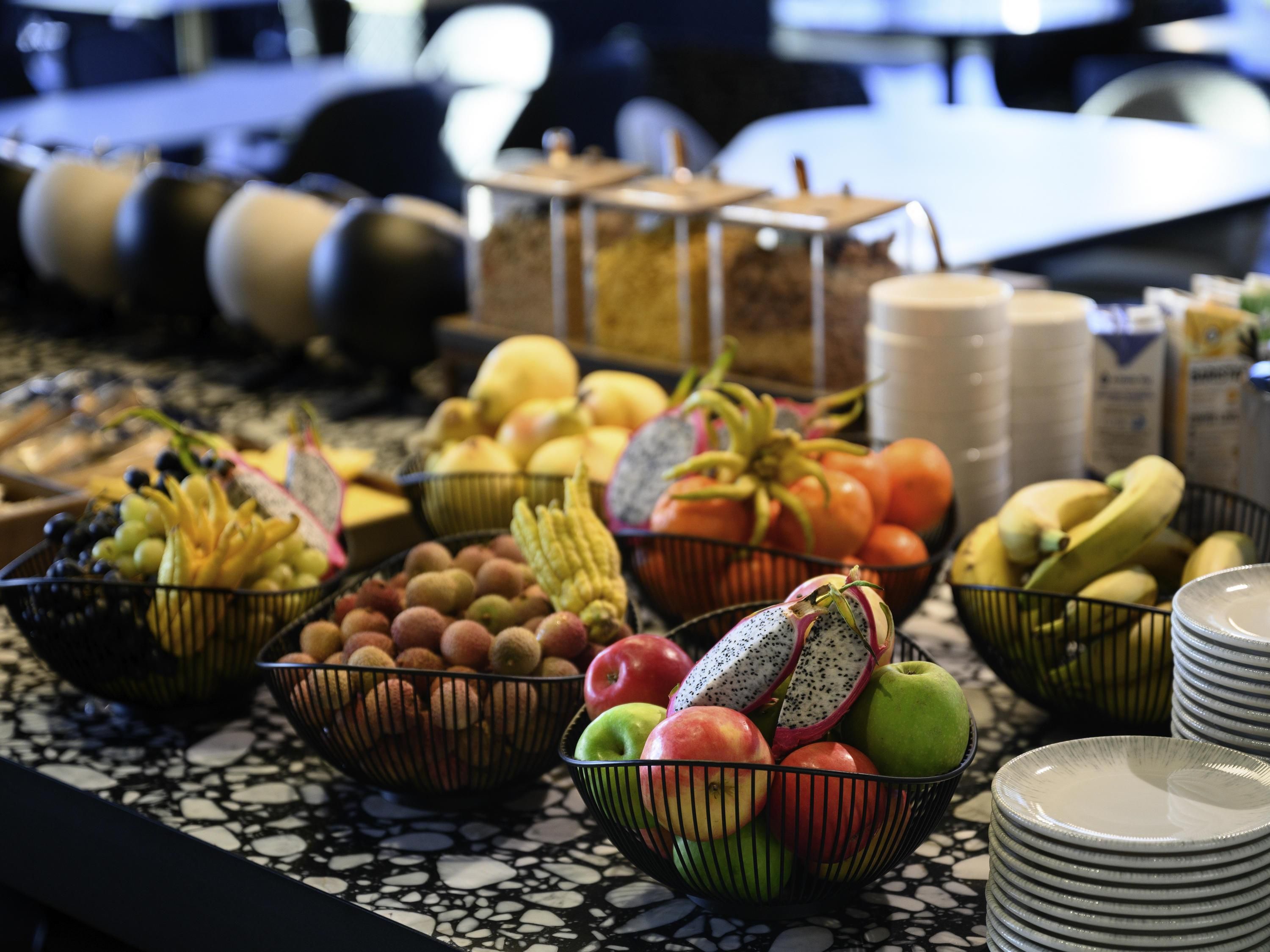 A buffet table with various fruits and vegetables, including apples, bananas, and tomatoes.
