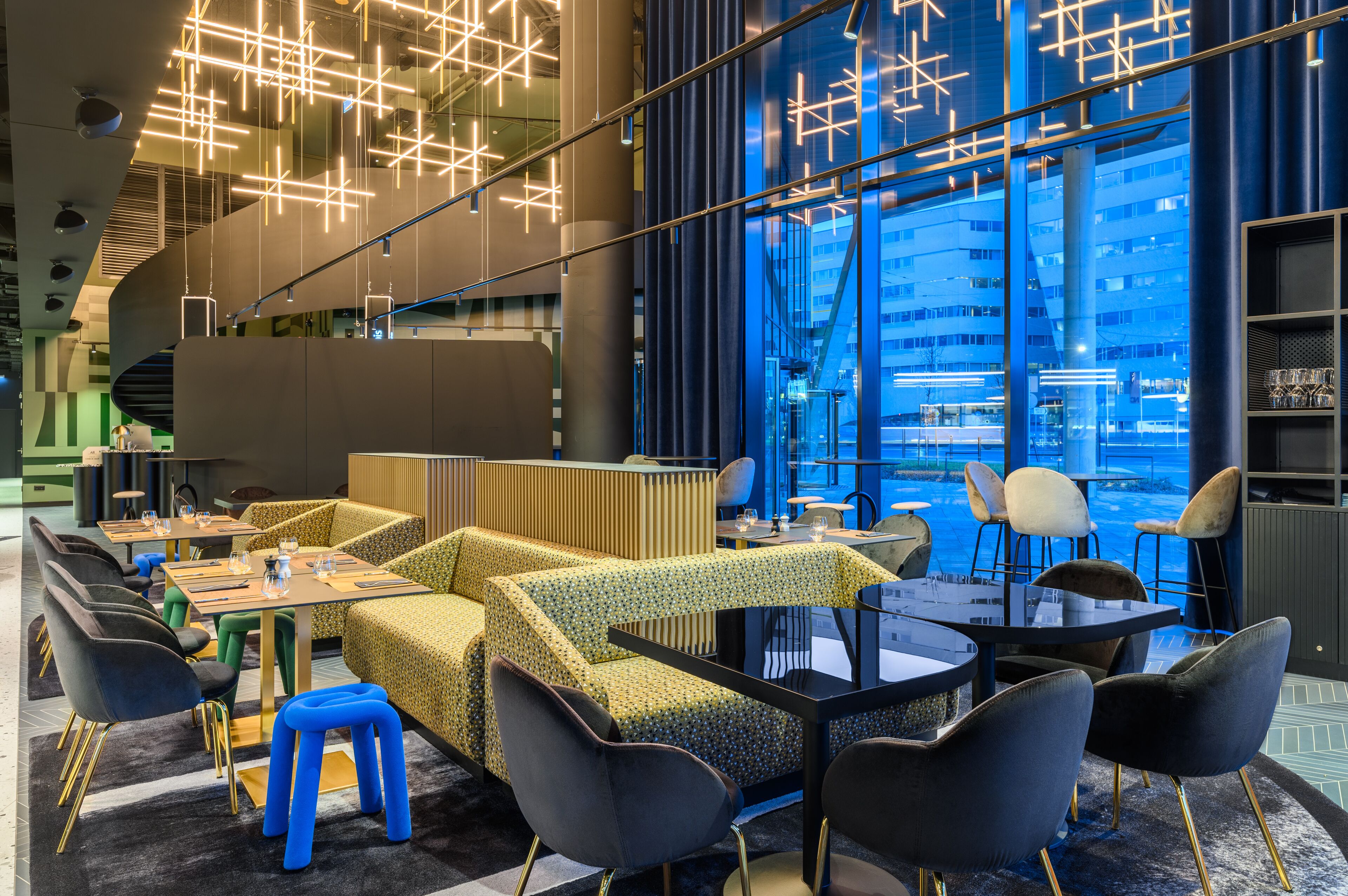 Un restaurante moderno con luminarias geométricas, una variedad de estilos de asiento y vistas de un paisaje urbano a través de amplios ventanales.