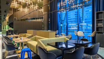Un restaurante moderno con luminarias geométricas, una variedad de estilos de asiento y vistas de un paisaje urbano a través de amplios ventanales.