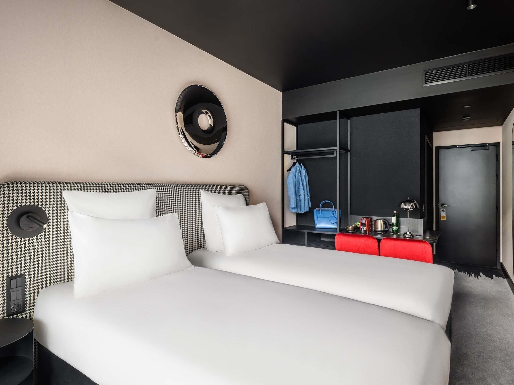 A hotel room with a large bed, a wardrobe, and a mirror on the wall.