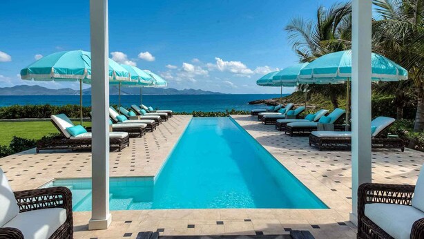 A poolside area with lounge chairs and umbrellas, a clear view of the ocean, and a mountain range in the distance. - Charming waterfront Caribbean estate - 2 min from pink sand beach (Little Harbour)