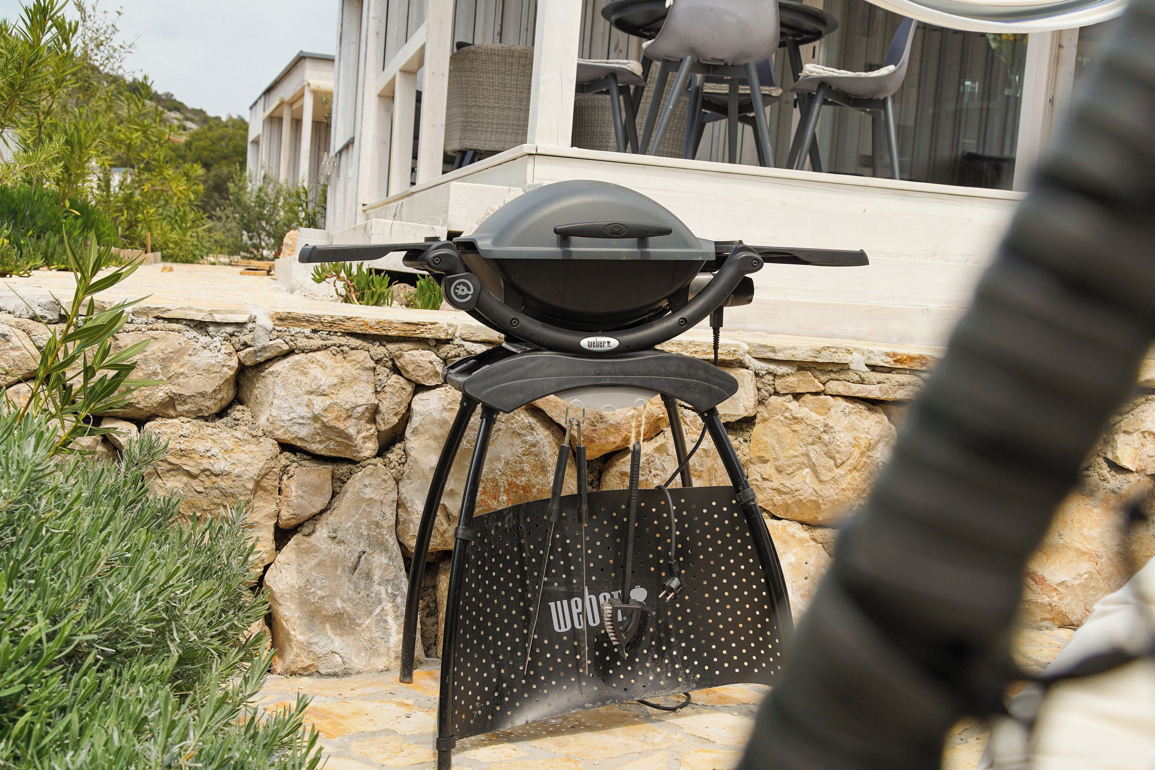A barbecue grill and a black bag with "Weg's" logo on a stone patio.
