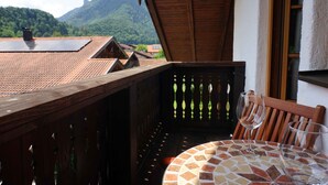 A balcony with a tiled table and two chairs, overlooking a mountainous landscape. - Sun II für 1-4 Personen, 60 m², Schlafzimmer, Wohn/schlafzimmer, Küche, Bad, Balkon, Wlan (Marquartstein)