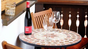 A round table with a mosaic tabletop, a bottle of wine, and two wine glasses. - Sun II für 1-4 Personen, 60 m², Schlafzimmer, Wohn/schlafzimmer, Küche, Bad, Balkon, Wlan (Marquartstein)