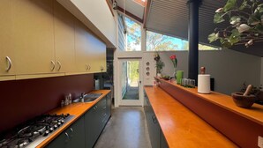 Une cuisine moderne dotée de plans de travail en bois, d’appareils électroménagers en acier inoxydable et offrant une vue sur l’extérieur.