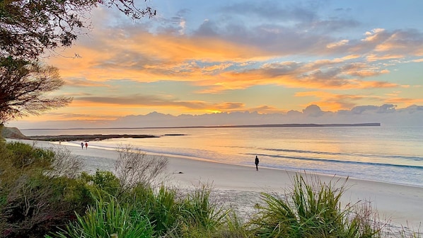 Ein Strand mit freiem Blick auf das Meer und entfernte Berge.