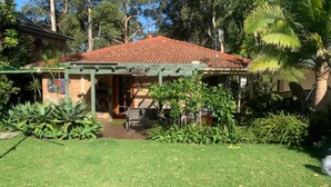 A house with a tiled roof, a covered patio, and a garden with various plants.