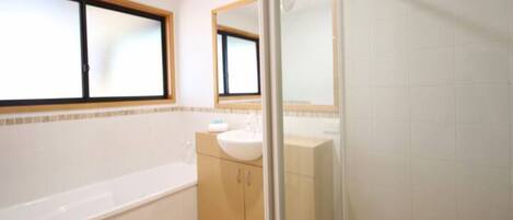 Une salle de bain avec une baignoire, un lavabo et un miroir.