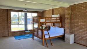 A room with a bunk bed, a small table, and a window with a view of the outside. - Sanctuary 79 by Book Jervis Bay - Family home located in Sanctuary Point (Sanctuary Point)