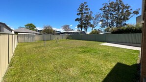 A backyard with a well-maintained lawn, a small tree, and a fence. - Sanctuary 79 by Book Jervis Bay - Family home located in Sanctuary Point (Sanctuary Point)