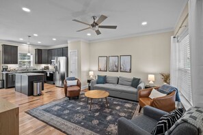 Un salon moderne avec un canapé, des fauteuils, une table basse et un tapis.