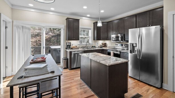Una cocina moderna con armarios oscuros, electrodomésticos de acero inoxidable y una isla grande.