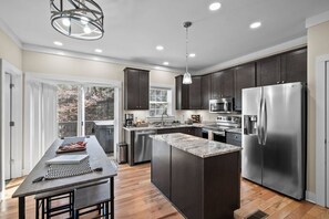 A modern kitchen with dark cabinets, stainless steel appliances, and a large island.