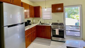Una cocina con armarios de madera, un refrigerador, una estufa y un lavamanos.