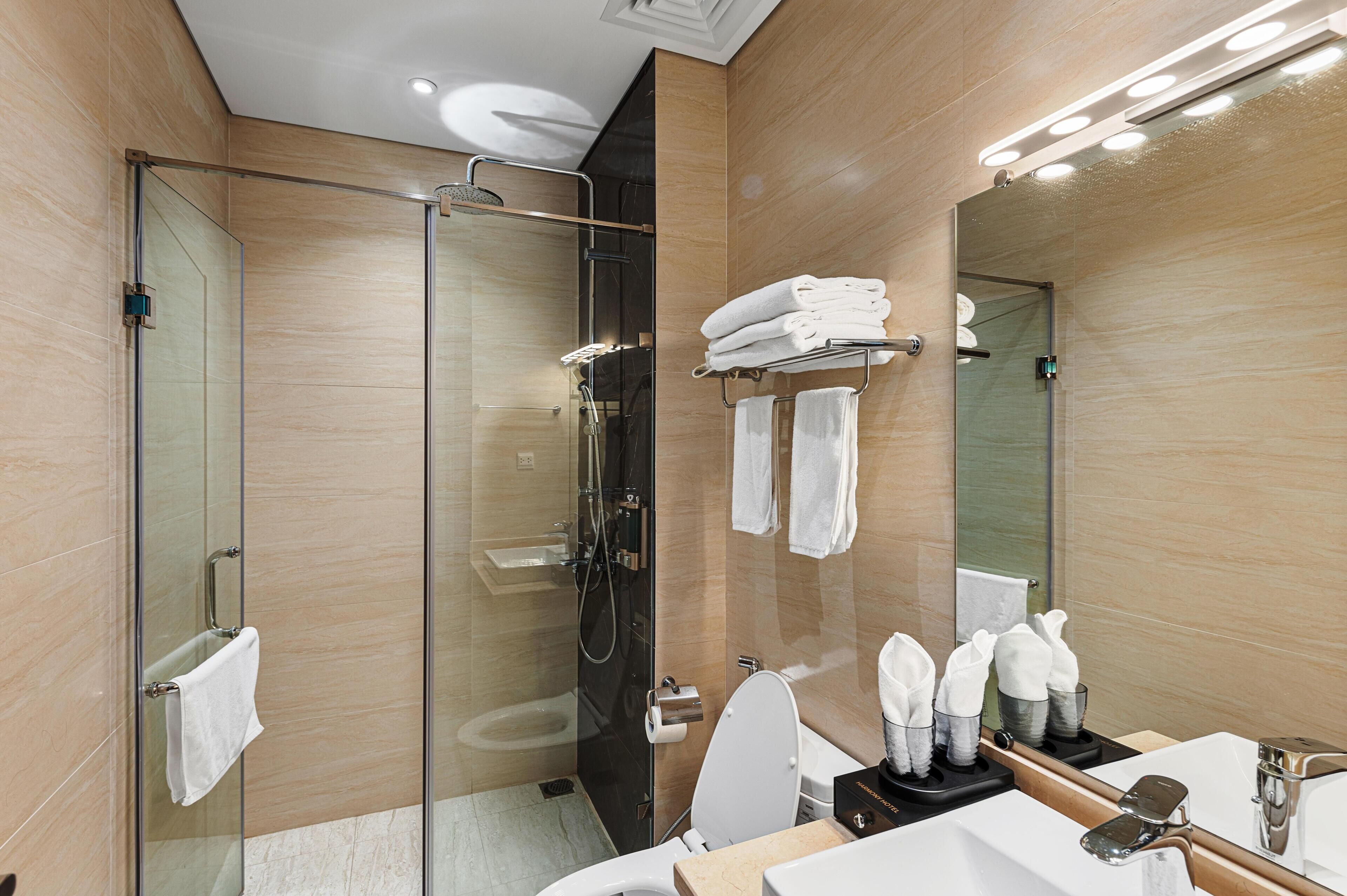 Une salle de bain moderne avec une douche à parois de verre, un lavabo avec un miroir et des serviettes soigneusement rangées.