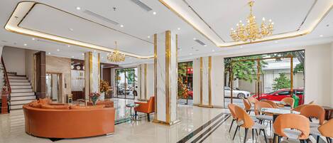 Un moderno vestíbulo de hotel con un sofá curvo, zona de comedor y una escalera.
