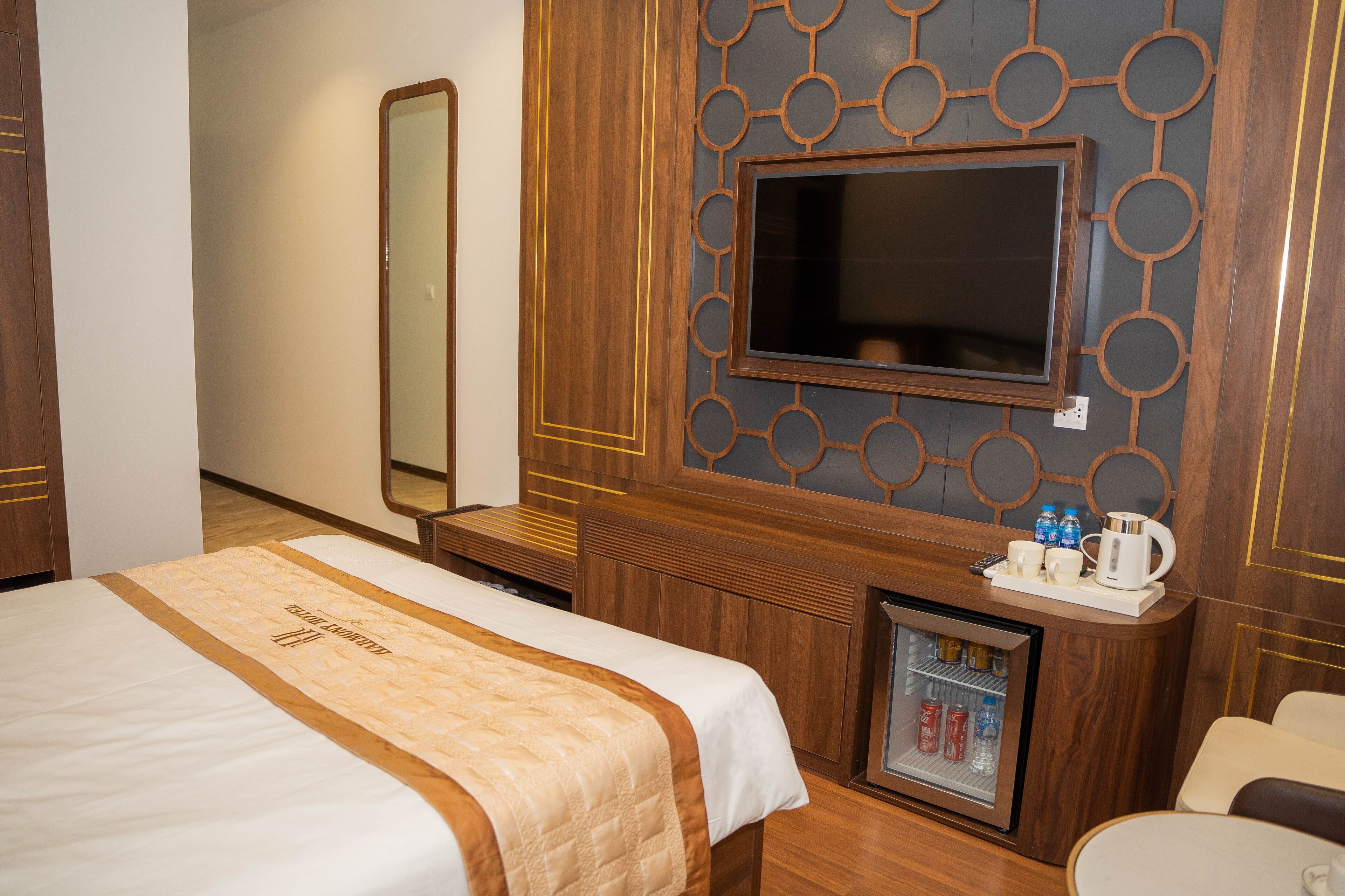 Ein Hotelzimmer mit Bett, Wandfernseher, Minibar und Sitzecke.