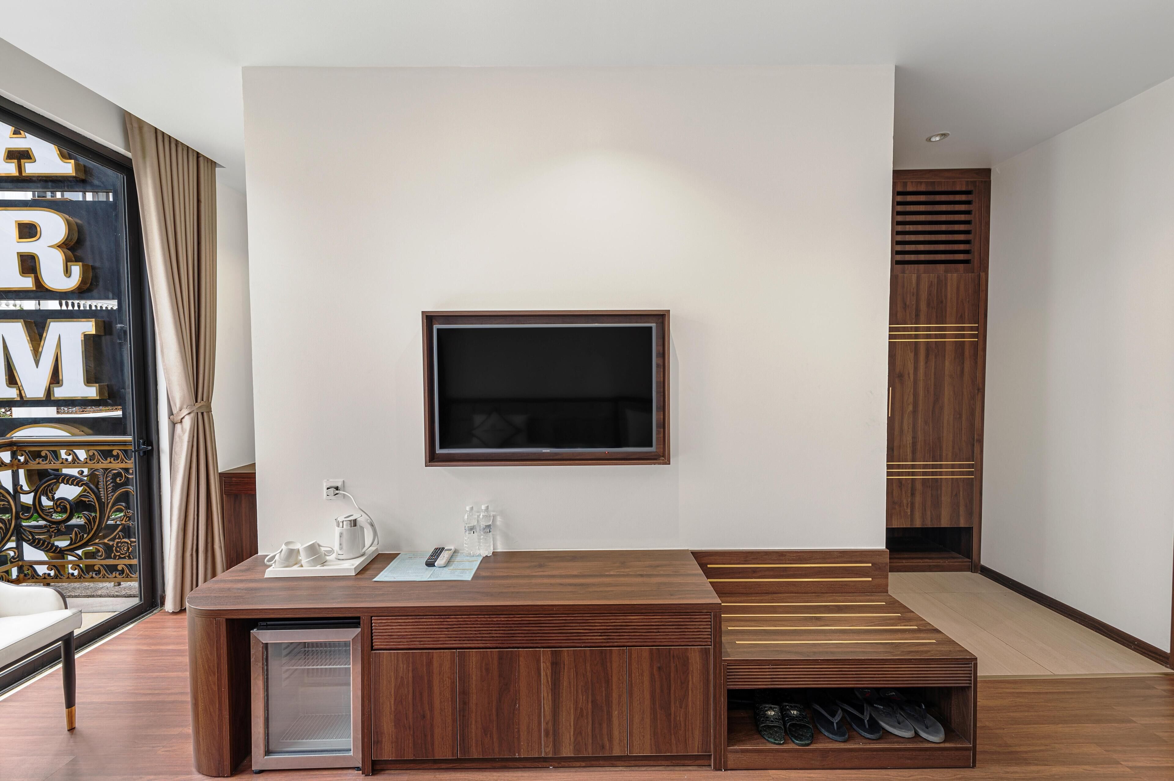 Un soggiorno moderno con una TV a parete, un tavolino in legno, una piccola credenza e un porta scarpe.
