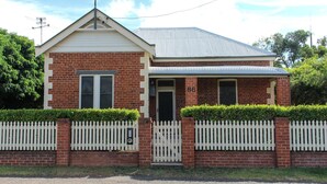 A two-story brick house with a front porch, a picket fence, and a number '86' on the door. - Family Retreat East Tamworth (East Tamworth)