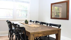 A dining area with a wooden table, black chairs, a small plant, and a mirror on the wall. - Family Retreat East Tamworth (East Tamworth)