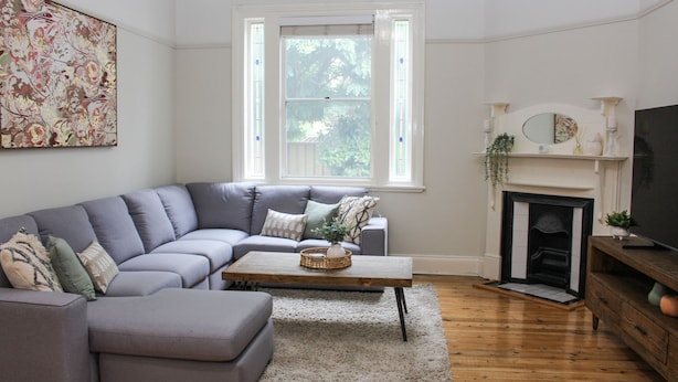 A living room with a grey sectional sofa, a wooden coffee table, a fireplace, and a large painting on the wall. - Family Retreat East Tamworth (East Tamworth)