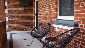 A brick exterior with two black wire chairs and a small window. - Family Retreat East Tamworth (East Tamworth)
