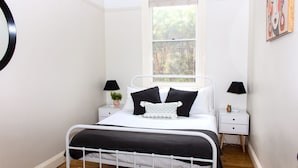 A bedroom with a bed, two bedside tables, a window, and a wall-mounted artwork. - Family Retreat East Tamworth (East Tamworth)