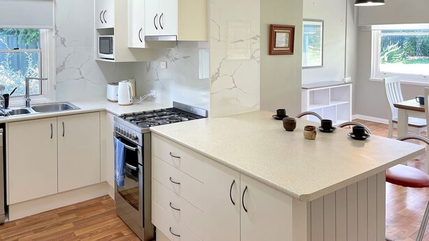 A modern kitchen with white cabinetry, a central island, and a view of the outdoors.