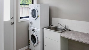 A compact laundry area with stacked washing machines and a sink. - Quintet 1-157 - North Tamworth (Tamworth)