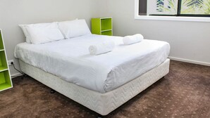 A neatly made bed with white bedding, a green nightstand, and a power outlet on the left. - Quintet 1-157 - North Tamworth (Tamworth)