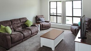 A living room with a brown leather sofa, a recliner, a white coffee table, and a television on a stand. - Quintet 1-157 - North Tamworth (Tamworth)