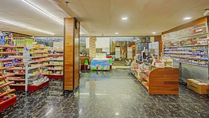 A pharmacy interior with shelves stocked with various products, a counter, and a display of Magnum liquor bottles. - Hotel O Jasmine 999 (Batam)