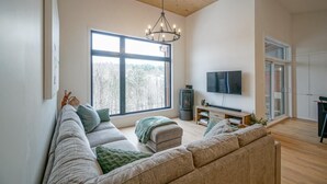 Una sala de estar moderna con un ventanal grande, una chimenea, un televisor de pantalla plana y una zona de estar acogedora.
