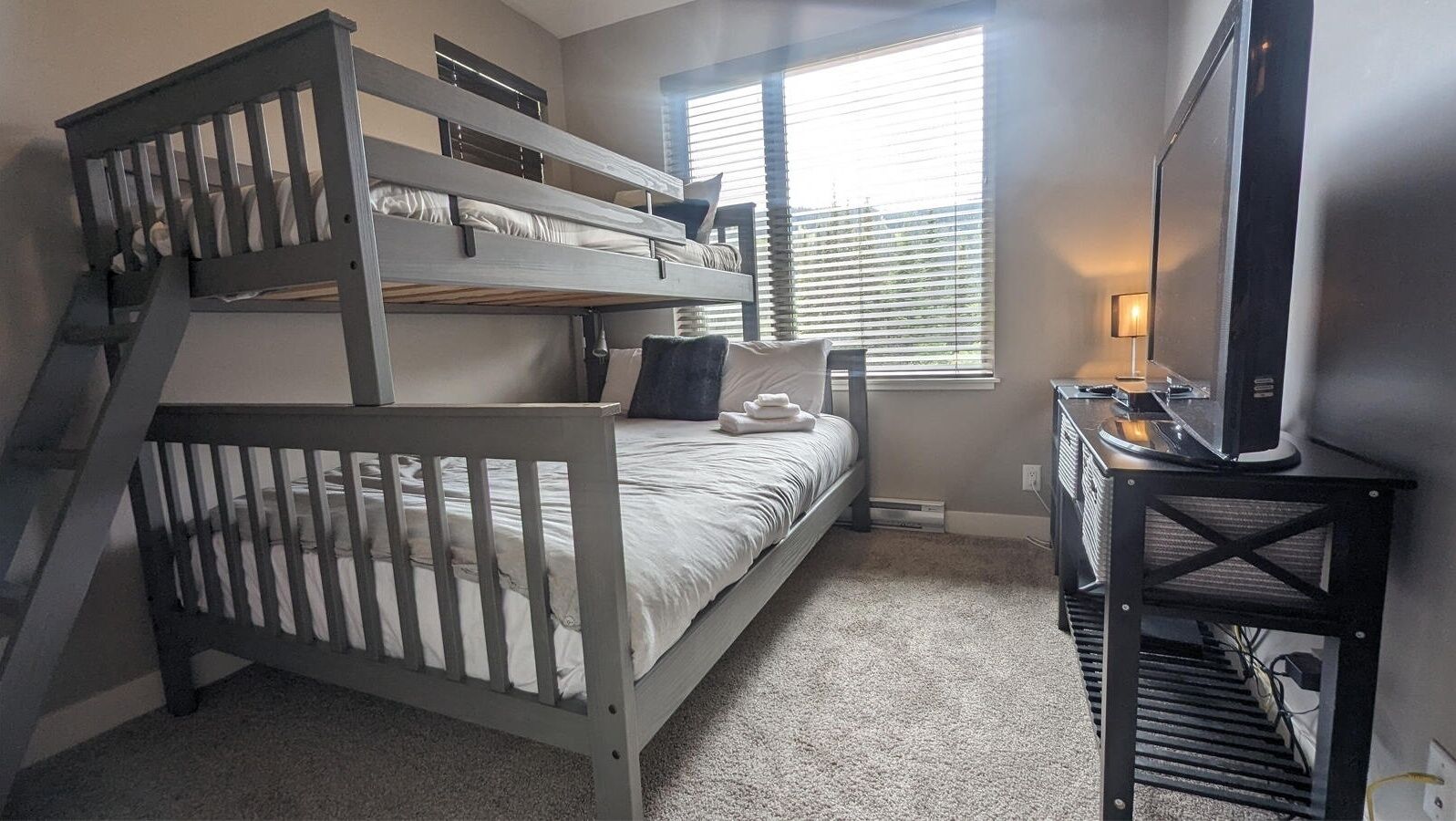 A bunk bed room with a desk and TV.