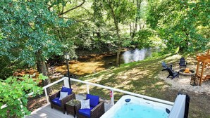 A deck with outdoor furniture, a hot tub, and a fire pit area surrounded by trees. - Creekfront! 5* Views, hot tub, fire pit, huge deck (Blue Ridge)