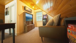 A cozy room with a wooden ceiling, a television mounted on the wall, a sofa, and a small table. - Creekfront! 5* Views, hot tub, fire pit, huge deck (Blue Ridge)
