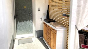 Une pièce dotée d’une porte-fenêtre coulissante, d’un meuble en bois, d’un petit lavabo et d’une fenêtre avec des stores.