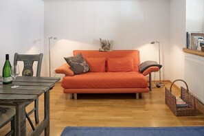 A room with a wooden table, a sofa, a floor lamp, and a basket.