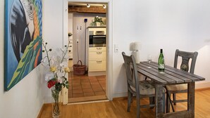 A dining area with a wooden table and chairs, a vase with flowers, and a painting on the wall. - Apartment "Gill" with Wi-Fi (Staufen)