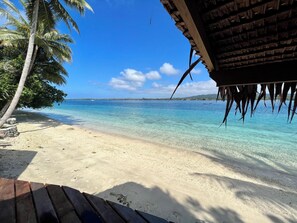 Una playa con agua turquesa cristalina, palmeras y una estructura de madera.