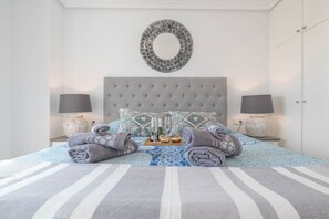 Un lit bien fait, avec une couvre-lit à rayures, deux oreillers et un miroir rond accroché au mur.