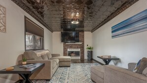 Una sala de estar con chimenea, dos sofás, una mesa de centro y un tapete estampado.